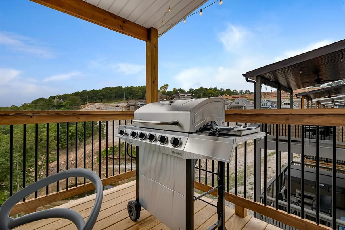 An inviting outdoor deck with a grill, spacious seating, and a panoramic scenic view, perfect for social gatherings or relaxing after a day of activities. The sunset hues in the sky hint at a lively evening atmosphere.