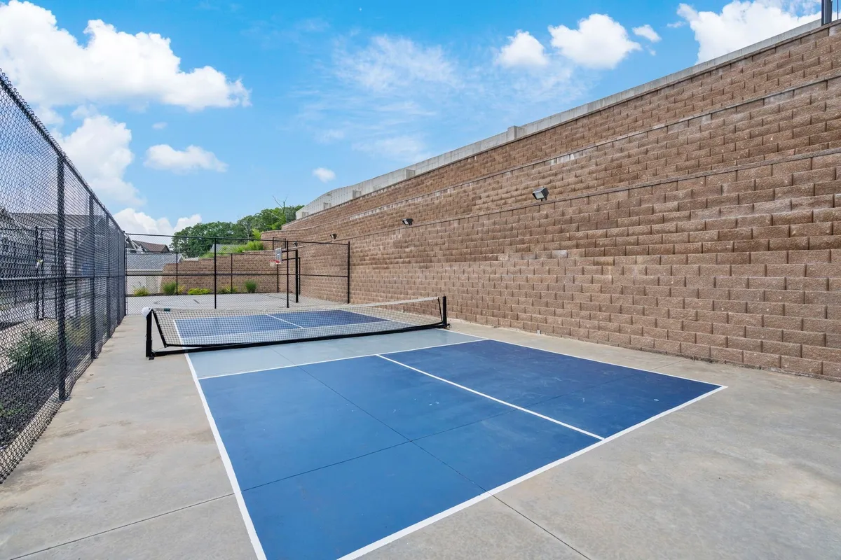 Lively pickleball courts surrounded by greenery, with groups of people enjoying friendly matches under the sun. The well-maintained courts and active participants create a sense of community activity and healthy outdoor living.