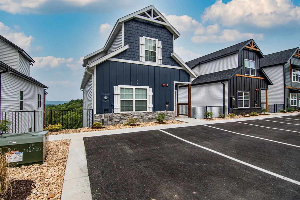 A welcoming exterior shot of a modern home with stone accents and a landscaped pathway leading to the entrance. The porch offers space for outdoor relaxation, and the scene is bathed in warm, inviting light.
